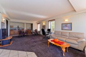 Executive Plus Inn and Suites في إيلك سيتي: غرفة معيشة مع أريكة وطاولة