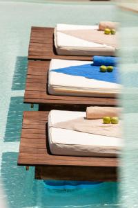 a row of four beds in a pool of water at Alexandra Golden Boutique Hotel-Adults Only in Chrysi Ammoudia