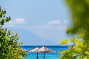 two umbrellas sitting on the beach near the ocean at Alexandra Golden Boutique Hotel-Adults Only in Chrysi Ammoudia