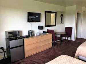 Lord Nelson Motel في كينغستون: غرفة في الفندق مع ميكروويف وطاولة مع كراسي