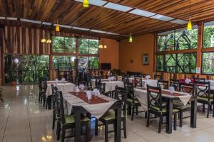a dining room with tables and chairs and windows at Jaguarundi Jungle Lodge - Monteverde in Monteverde Costa Rica