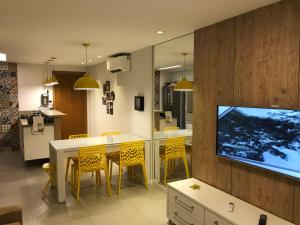 a kitchen and dining room with a tv on a wall at Lindo Apto 2/4 em Guarajuba in Guarajuba