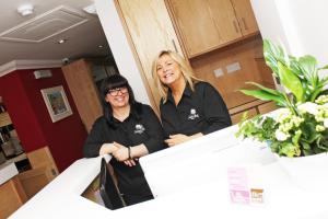 dos mujeres de pie detrás de un mostrador en una cocina en Gidea Park Hotel, en Romford