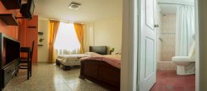 a bedroom with a bed and a sink and a toilet at Hostal La Rosa Otavalo in Otavalo