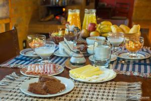 einen Tisch mit Teller mit Lebensmitteln und Gläsern Milch in der Unterkunft Pousada da Oma in Cunha