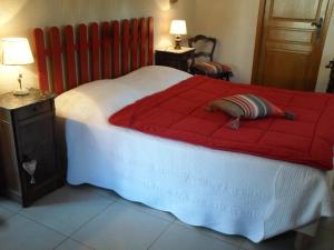 a bedroom with a large bed with a red comforter at La Grange du Bourg in Deneuille-les-Mines