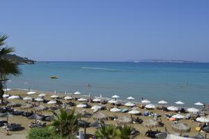 a beach with a lot of umbrellas and the ocean at Delfino Blu Wellness Boutique Hotel in Agios Stefanos