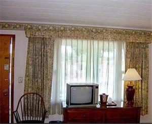 a living room with a tv and a dresser at West Road Motel in Bennington