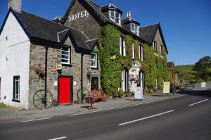 a building with a red door on the side of a street at The Cuilfail Hotel in Kilmelfort