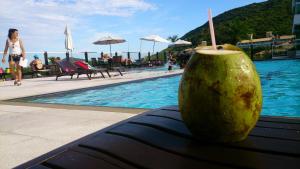 um coco sentado num banco ao lado de uma piscina em Águas do Santinho Apart em Florianópolis