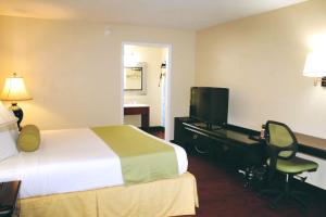 a hotel room with a bed and a desk and a television at Residence Hub Inn and Suites in Marianna