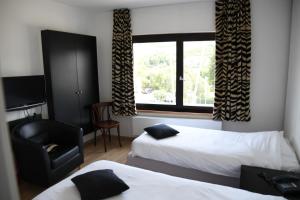 a hotel room with two beds and a chair and a window at L'Auberge Saint Remacle in Stavelot