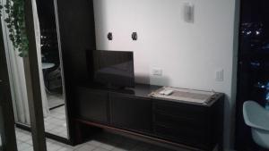a bathroom with a tv on a dresser with a mirror at Aconchegante Flat na Orla in Recife