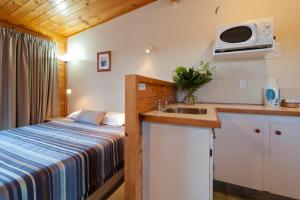 a small kitchen with a bed and a sink at Outrigger Motel in Paihia