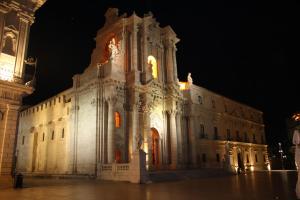 un gran edificio blanco con una torre de reloj por la noche en Il Duomo en Siracusa