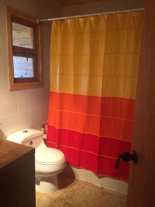 y baño con cortina de ducha colorida y aseo. en Casa Playa, en Navidad