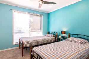Duas camas num quarto com paredes azuis e uma janela em NewPort Dream Quiet Island - No Party Maximum 9-10 People em Redcliffe