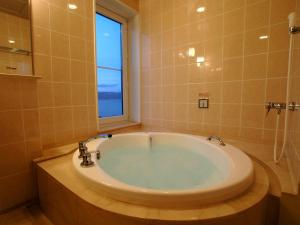 a bath tub sitting next to a window in a bathroom at Kussharo Prince Hotel in Teshikaga
