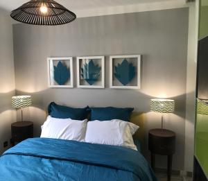a bedroom with a blue bed with three pictures on the wall at Le Petrel Blanc - Appartement sur la plage de la Souris Blanche in Trois Bassins