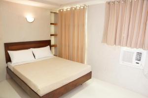 a small bedroom with a bed and a window at Hotel Rodolfo in Tacloban