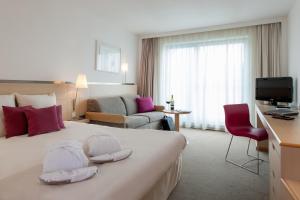 a hotel room with a bed, chair, desk and a television at Novotel Berlin Mitte in Berlin