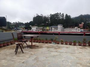 a patio with a table and chairs on a roof at Hotel Preethi Palace in Ooty