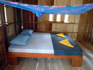 a bed in a wooden room with a canopy at Koh Thmei Resort in Phumĭ Kâng Kéng