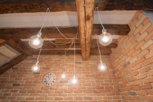 a group of lights hanging from a brick wall with a clock at Ca del Pape in Venice
