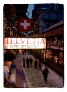 un grupo de personas caminando frente a un restaurante del hotel en Petit Helvetia Budget Hotel en Zermatt