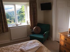 a bedroom with a green chair and a window at Zeal Farm in Dulverton