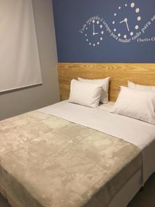 un letto con cuscini bianchi e un orologio a parete di Loft New York a Niterói