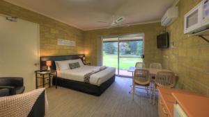 a bedroom with a bed and a table and chairs at Yarra Holiday Park in Stuarts Point