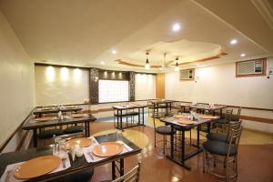 ein Restaurant mit Tischen und Stühlen in einem Zimmer in der Unterkunft Hotel Grand Arjun in Raipur