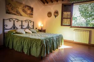 バルベリーノ・ディ・ヴァル・デルサにあるAgriturismo Fattoria Sant'Appianoのベッドルーム1室(緑色のベッドカバー付)、窓が備わります。
