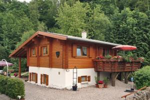 a log cabin with a balcony and an umbrella at Apartments Am Kupferberg in Walkenried
