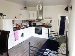 a kitchen with white cabinets and a wooden floor at Ferienwohnung Talblick in Eisenach