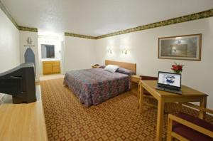 ein Hotelzimmer mit einem Bett, einem Schreibtisch und einem TV in der Unterkunft Americas Best Value Inn Weatherford in Weatherford