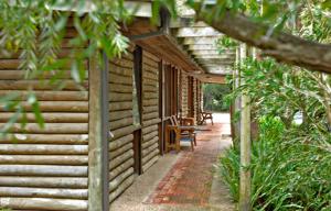 a log cabin with a porch and a table at Mallacoota Log cabins in Mallacoota