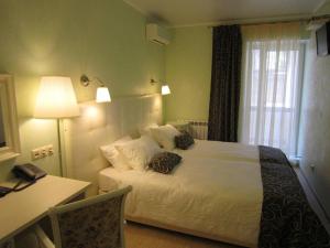 1 dormitorio con cama, escritorio y lámpara en Avantazh Hotel en Saratov