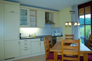 グロヴェにあるDünenresidenz Glowe - Haus Lenaの白いキャビネット、テーブルと椅子付きのキッチンが備わります。
