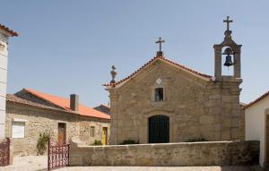 a stone church with a bell tower and a cross at Solar dos Caldeira e Bourbon in Zebras