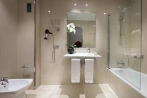 a bathroom with a sink, mirror, and tub at Eurostars Regina in Seville