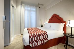 a hotel room with a bed, chair, and nightstand at Eurostars Regina in Seville