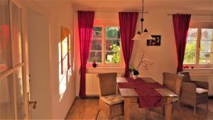 a living room with a dining room table with chairs and red curtains at Villa Terracotta in Eisenach
