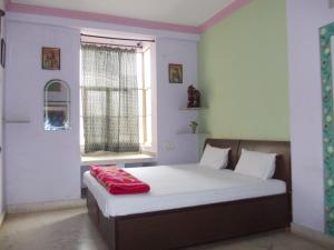 a bedroom with a bed with a red blanket on it at Raj Mahal Guest House in Būndi
