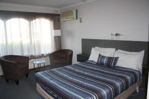 a hotel room with a bed and a table and chairs at Raglan Motor Inn in Warrnambool