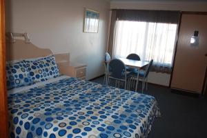a hotel room with a bed and a table with chairs at Raglan Motor Inn in Warrnambool