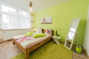 a green bedroom with a bed and a mirror at Ferienwohnung Moderne Mitte in Eisenach