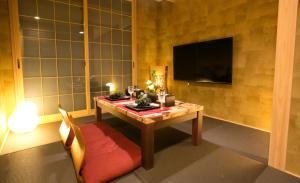 京都市にあるホスタ東寺 燦のテーブル、テレビ、椅子が備わる客室です。
