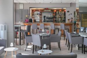 a restaurant with tables and chairs and a bar at Hotel Club Le Capet in Sainte-Maxime